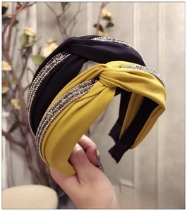 Détail du bandeau en tissu torsadé avec bandes de strass brillants en bleu marine et jaune
