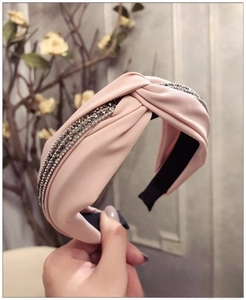 Détail du serre-tête torsadé rose avec rangées de strass argentés et finition satinée