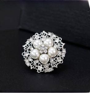 Close-up of a silver-tone brooch with five pearls and sparkling rhinestones for women