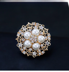 Detail of gold floral brooch featuring five large white pearls and crystal accents