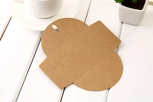 Flat lay of brown kraft paper pillow box with heart shape detail on white wooden desk