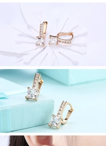 Detail of square-cut zircon hoop earrings in gold finish featuring a layered display