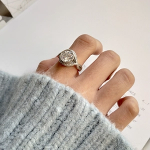 Detail of a large round-cut zircon silver ring with pavé halo on a female hand