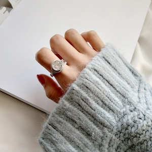 Detailed close-up of a silver ring with large round-cut sparkling gemstone on hand