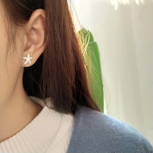 Close-up of sparkling starfish stud earrings in silver on model ear for style