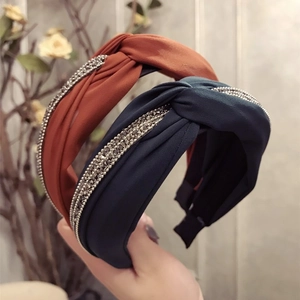 Serre-têtes en tissu noué orange et bleu marine avec strass brillants tenus à la main