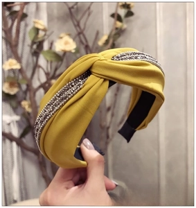 Détail d'un serre-tête moutarde à nœud avec texture en tissu et rangées de strass