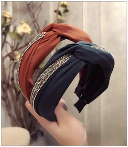 Détail du serre-tête croisé avec bordures en strass brillants en bleu marine et rouge brique