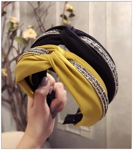 Détail du serre-tête en tissu croisé avec double rangée de strass en noir et jaune