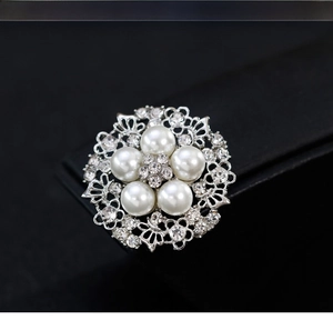 Detailed close-up of retro silver alloy brooch with white pearls and sparkling crystals