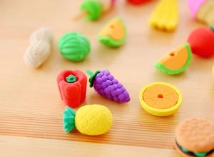 Macro shot of assorted colorful fruit and food shaped erasers on a wooden table