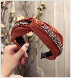Détail du serre-tête large noué orange avec double rangée de strass et de perles