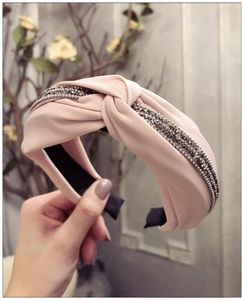 Détail du serre-tête en tissu rose avec strass gris étincelants et motif à nœuds