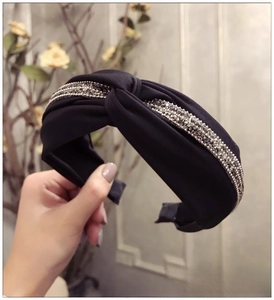 Détail du serre-tête torsadé en satin noir avec trois rangées de strass gris étincelants