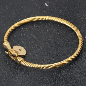 Detail showing the 18K gold cable twist texture and heart lock pendant on the bracelet