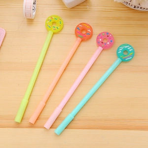 Set of four creative donut-topped gel pens in pastel colors on wooden desk