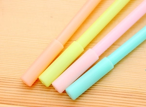 Detailed view of four macaron-colored plastic pens on a light wood grain desk