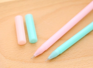 Close-up of pink and mint green lollipop-style gel pens on a light wood surface