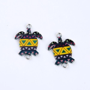 Macro detail of colorful sea turtle metal charms with geometric pattern and double loops