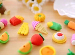 Macro shot of assorted food-shaped erasers including fries and strawberry on wood surface
