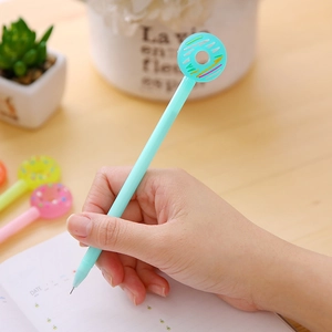 Teal donut-topped creative gel pen held by hand writing on a paper notebook