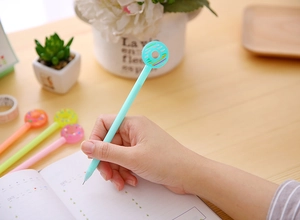 Close-up of hand writing with a blue donut-shaped gel pen on a desk calendar