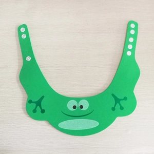 Green frog cartoon baby shower cap with adjustable strap on a wooden background