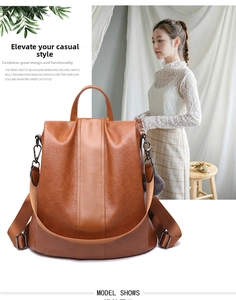 Dettaglio dello zaino vintage in pelle marrone con ciondolo a pompon e spalline