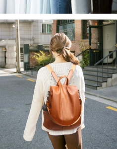 Vista street style di una donna con zaino in ecopelle marrone scuro e dettaglio pompon