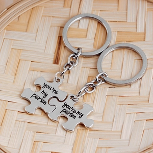 Detail of silver puzzle piece keychains with 'you're my person' text on bamboo tray