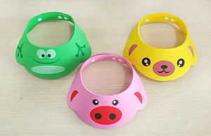 Detailed view of baby shower caps in green frog, pink pig, and yellow bear cartoon shapes