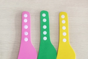 Detail of adjustable silicone straps in pink, green and yellow with five white snap buttons