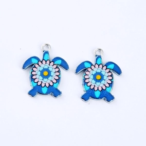 Detailed close-up of blue turtle charms with colorful floral enamel patterns and metal rings