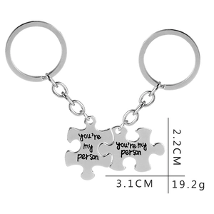 Silver puzzle piece keychains with 'you're my person' engraving and size measurements