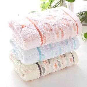 Detailed stack of pink, blue, and beige textured cotton face towels with diamond pattern