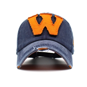 Macro shot of the vintage navy cotton baseball cap featuring an orange embroidered W letter