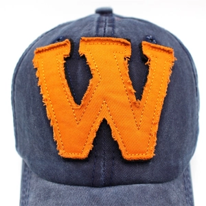 Macro view of orange embroidered letter W on vintage washed navy cotton baseball cap