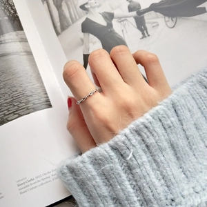 Close-up of a vintage 925 silver knotted ring worn on a hand against a fashion magazine