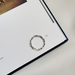 Macro detail of retro 925 sterling silver knotted chain ring on white book pages