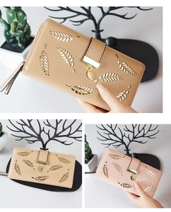 Detail of minimalist long wallet featuring hollow leaf pattern and metal leaf pendant