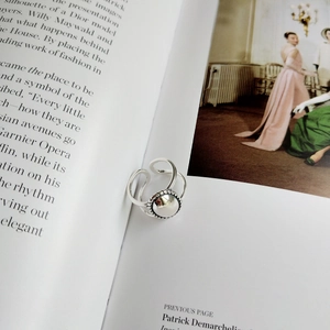 Detailed close-up of a 925 sterling silver minimalist open ring on a magazine page