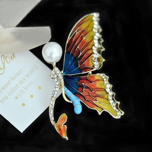 Detailed close-up of a tricolor enamel butterfly brooch with rhinestones and a white pearl