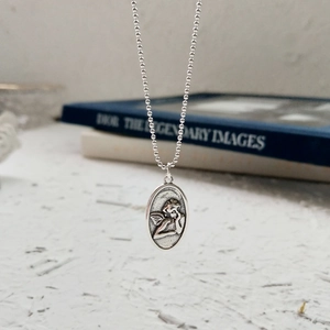 Detailed view of vintage 925 sterling silver guardian angel relief on oval pendant