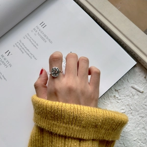 Detail of vintage silver relief ring worn against an aesthetic book background