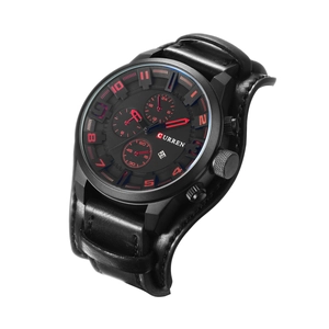 Detail view of large black watch face with red indices and calendar on leather strap