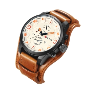 Detail view of brown leather strap and beige dial with orange markers on men's watch