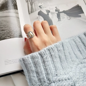 Macro detail of retro 925 silver ring featuring an oval cabochon and woven edge textures