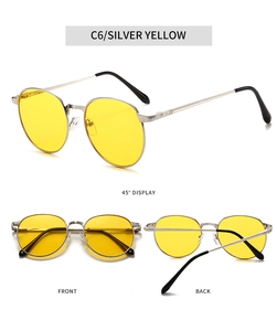 Detail view of silver oval sunglasses with yellow lenses and engraved spring hinges