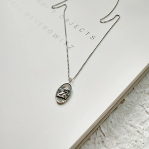 Close-up of vintage S925 sterling silver angel relief pendant on a white book page