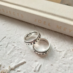Detailed close-up of rotating sterling silver rings with star and moon patterns on a book